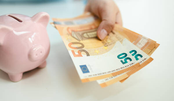 Business piggy bank with a coin on a white table. Man hand holds euro banknotes to pay bills. Business finance saving and investment concept.